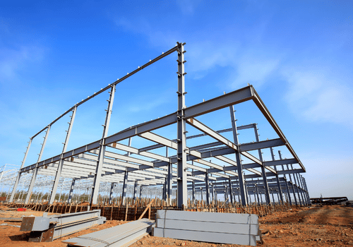 Pre-engineered steel building frame under erection with members on the ground