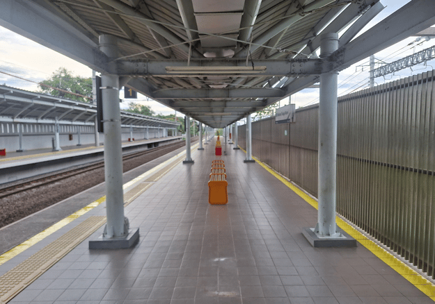 Covered railway platform walkway under a steel platform shed