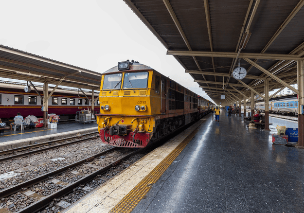 Steel railway platform shed with a roof canopy over the platform and a train alongside